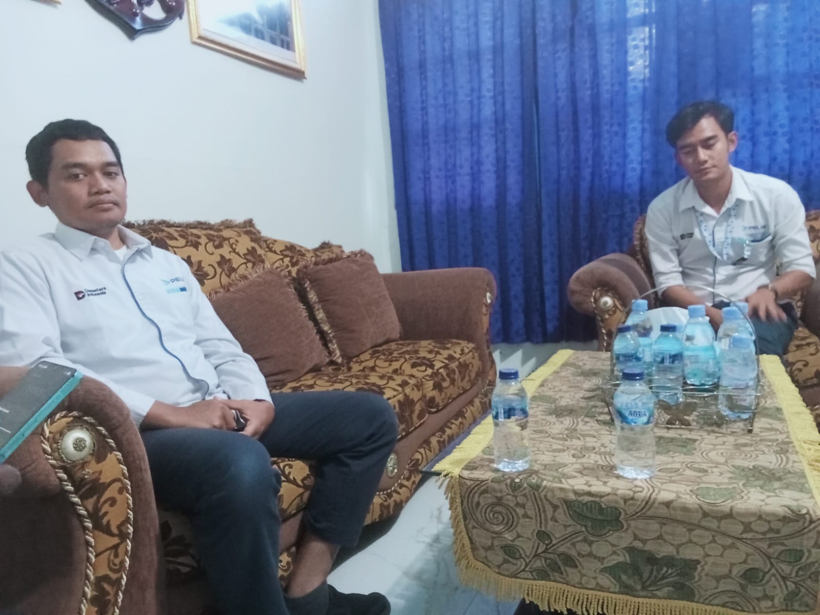Kepala Cabang PT Pelni Dobo duduk bersama staf di ruang tamu kantor, mengenakan seragam putih dengan logo perusahaan, membahas kebijakan barang bawaan penumpang kapal Pelni.