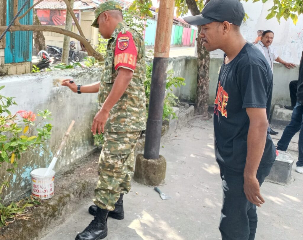Babinsa bersama warga bekerja sama melakukan pengecatan pagar di lingkungan Kelurahan Galaydubu.
