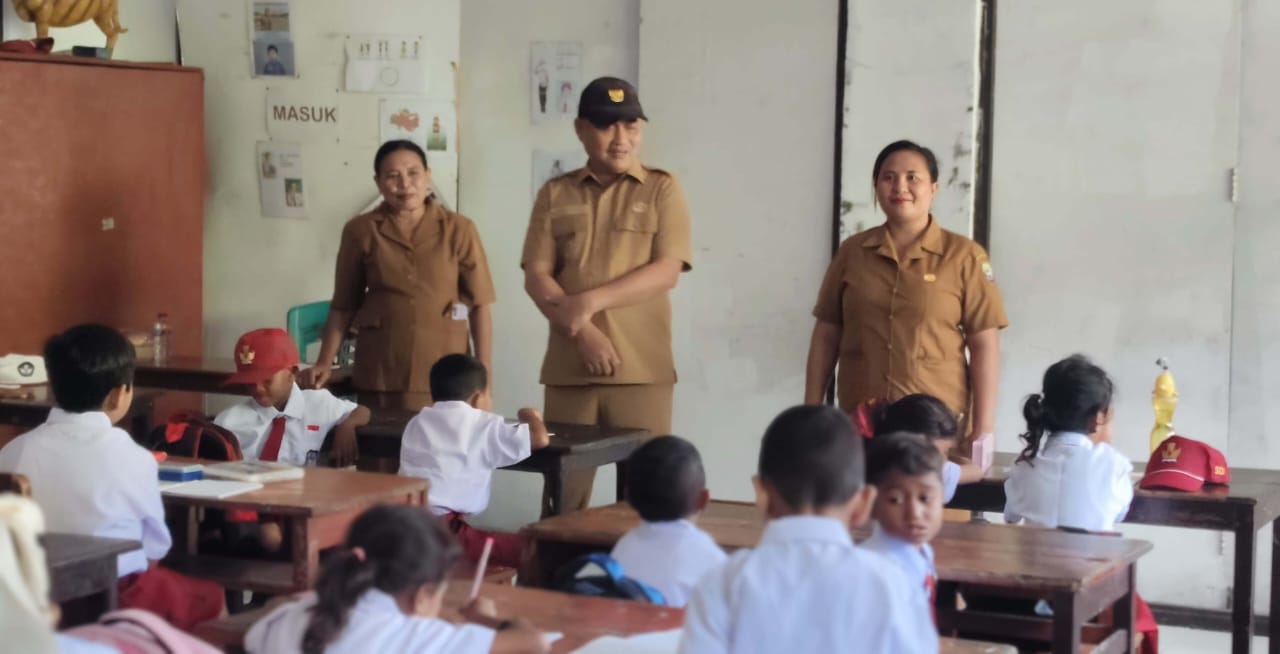 Bupati Kepulauan Aru bersama guru berdiri di depan kelas saat memantau kegiatan belajar siswa di hari pertama sekolah.
