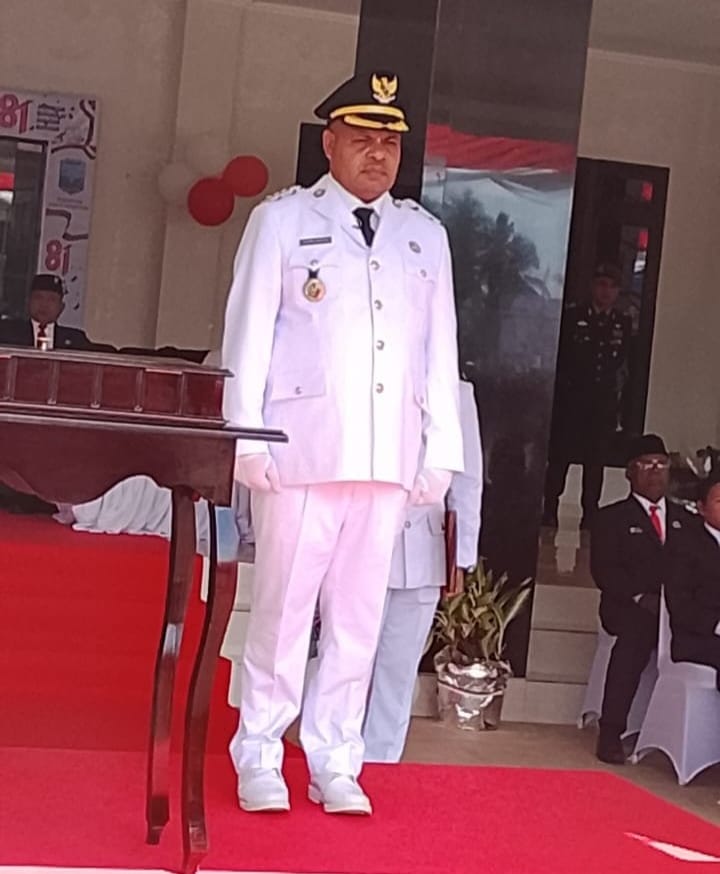 Bupati Heronimus Mansoben mengenakan pakaian dinas upacara putih lengkap dengan topi kebesaran saat memimpin upacara HUT RI ke-81 di Supiori.