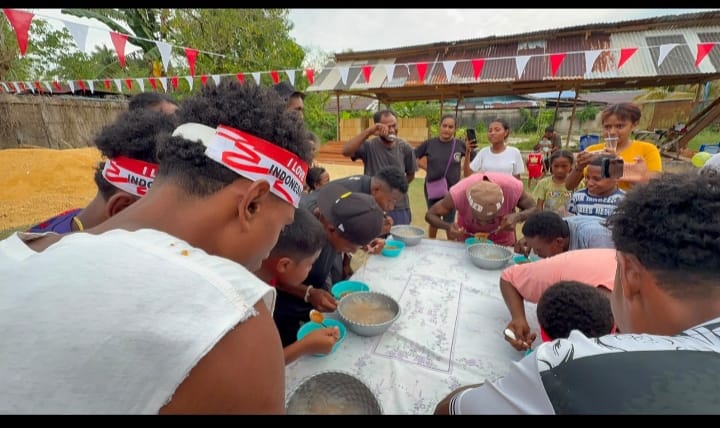 Peserta lomba tradisional di Sorendiweri beradu cepat makan dalam suasana meriah di bawah hiasan bendera merah putih.