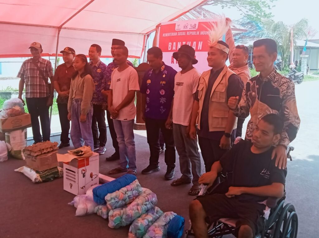 Wakil Bupati Kepulauan Aru berfoto bersama penerima manfaat dan tim Dinas Sosial di bawah tenda kegiatan penyaluran Bantuan Atensi Kemensos 2026.
