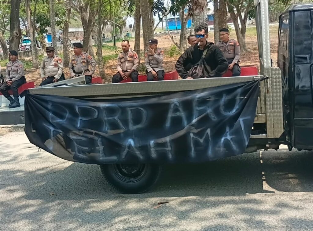 Mobil bak terbuka membawa spanduk hitam bertuliskan DPRD ARU TELAH MATI saat aksi unjuk rasa di Kepulauan Aru.