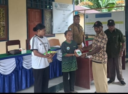Penyerahan secara simbolis paket bibit sayuran dari pejabat lokal kepada warga penerima manfaat di Kampung Warbefondi.