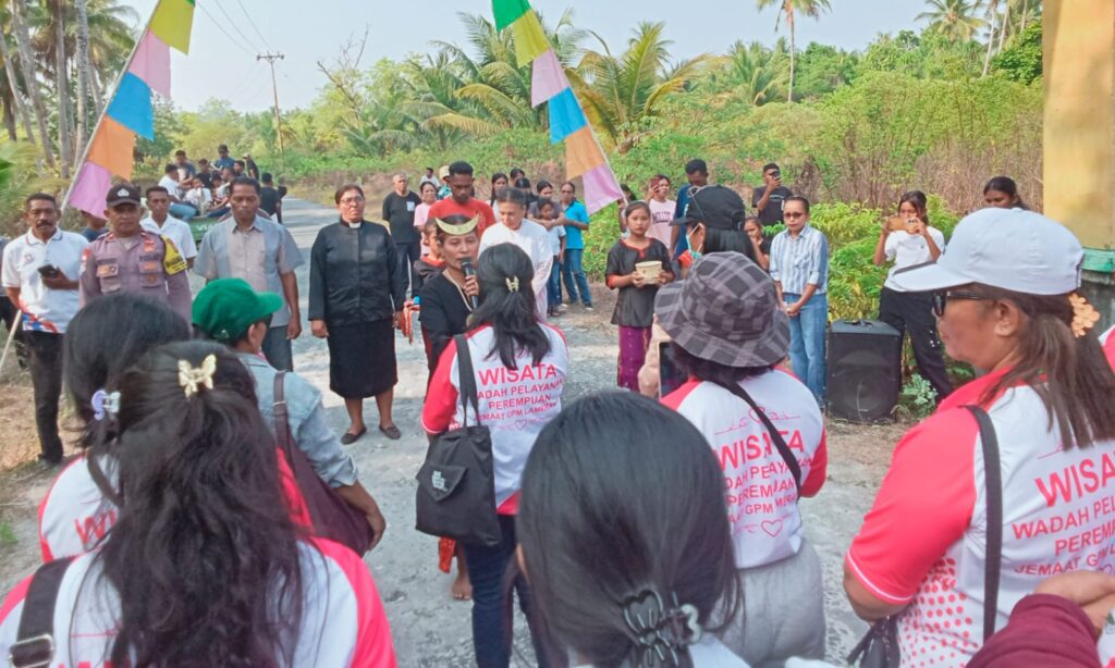 Rombongan jemaat mengenakan seragam seragam khusus berjalan bersama dalam kegiatan wisata rohani di jalur pedesaan