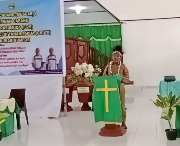 Pembicara mengenakan pakaian adat Papua berdiri di mimbar gereja menyampaikan sambutan pada Muscab I FGM GKI TP Biak Numfor