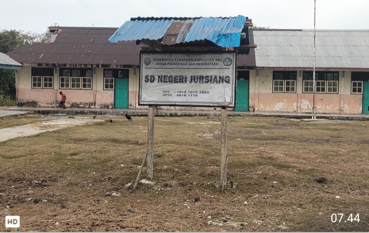 Papan nama SD Negeri Jursiang Kabupaten Kepulauan Aru berlatar belakang bangunan sekolah yang sepi tanpa aktivitas murid